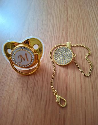 Zlatý cumlík a klip s písmenom m, 