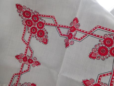 Červená ručná výšivka na bielom podklade,